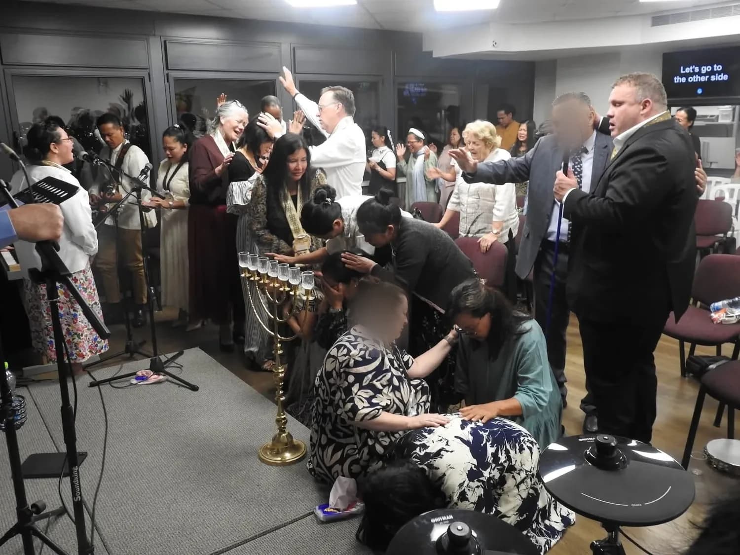 Believers laying hands and praying together at a weekly service in Israel