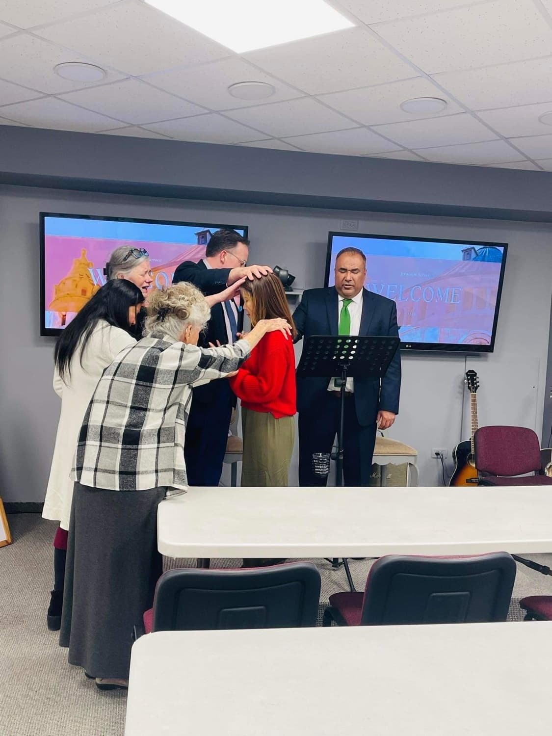 Believers laying hands and praying together at a weekly Jerusalem service